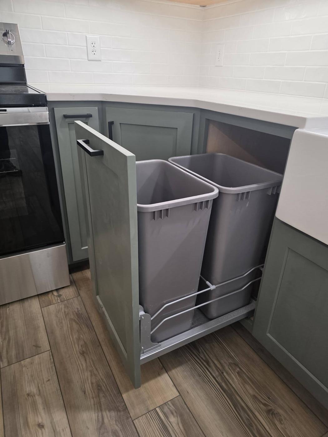 Sage-green base cabinets with a pull-out double bin