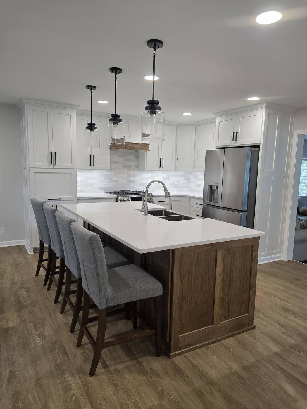 A finished white shaker kitchen with an oak island and gray stacked-tile backsplash