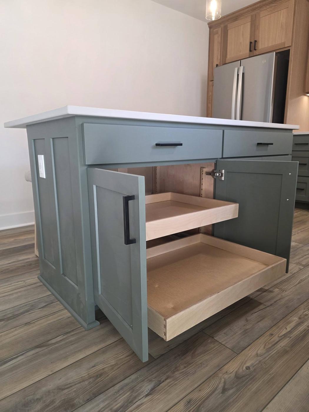 A sage-green island opened to show full-extension timber pull-out shelves