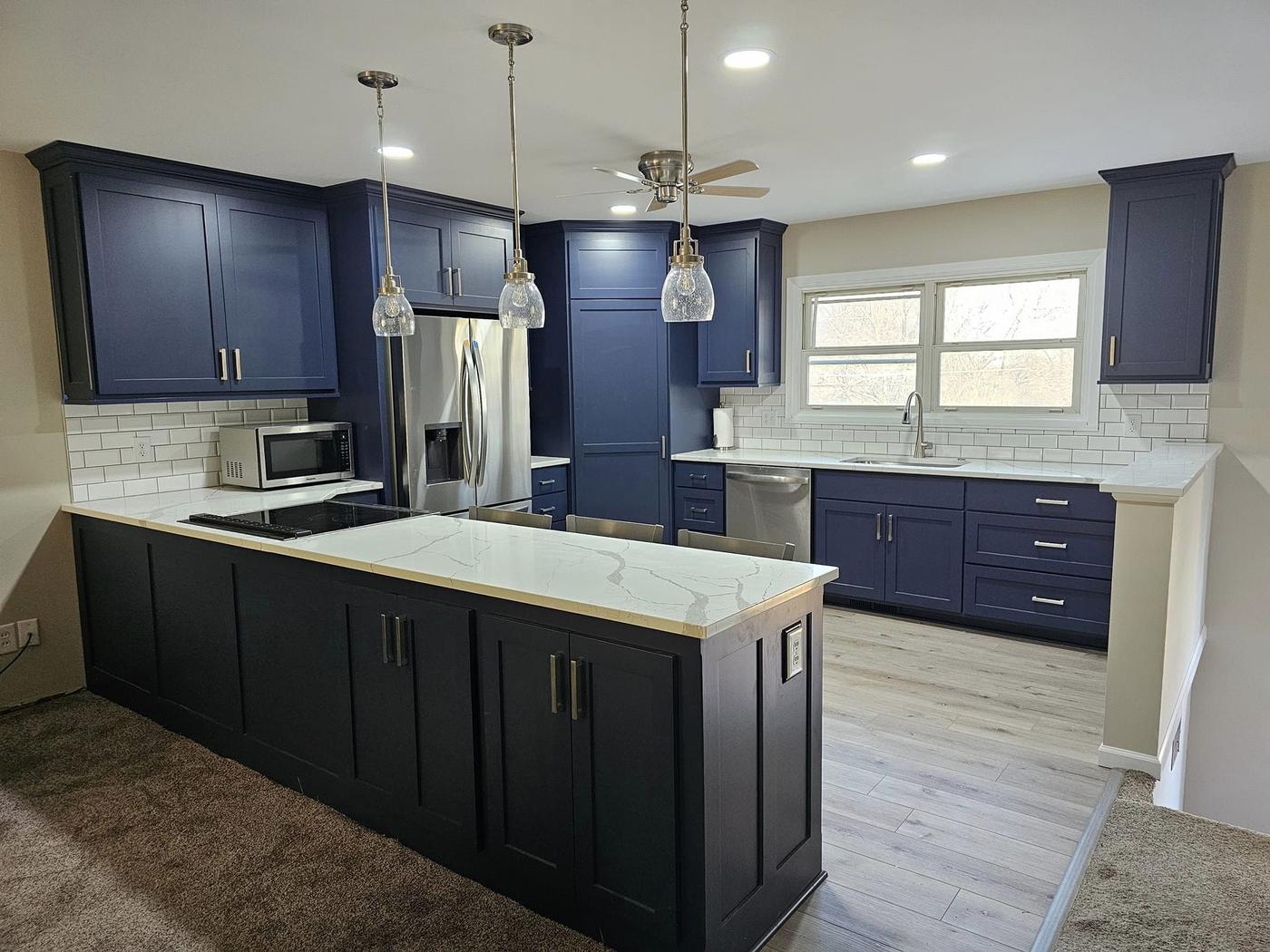 A finished kitchen in deep navy shaker cabinets with a white quartz island