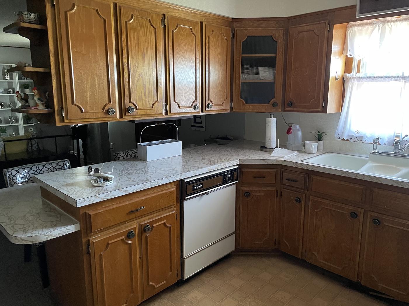 A dated kitchen with oak raised-panel cabinets and marbled laminate counters